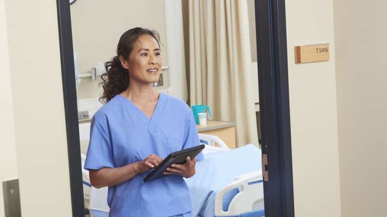 Nurse in Hospital Room with Tablet